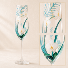 Close-up details of hand-painted orchids and teal botanical leaves on champagne glass
