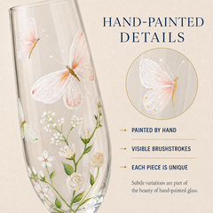 Close-up of hand-painted white and blush butterflies, wildflowers, leaves and visible brushstrokes on champagne glass