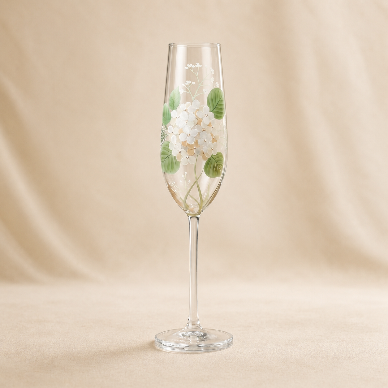 Hand-painted white hydrangea champagne flute with green leaves on a soft neutral background.