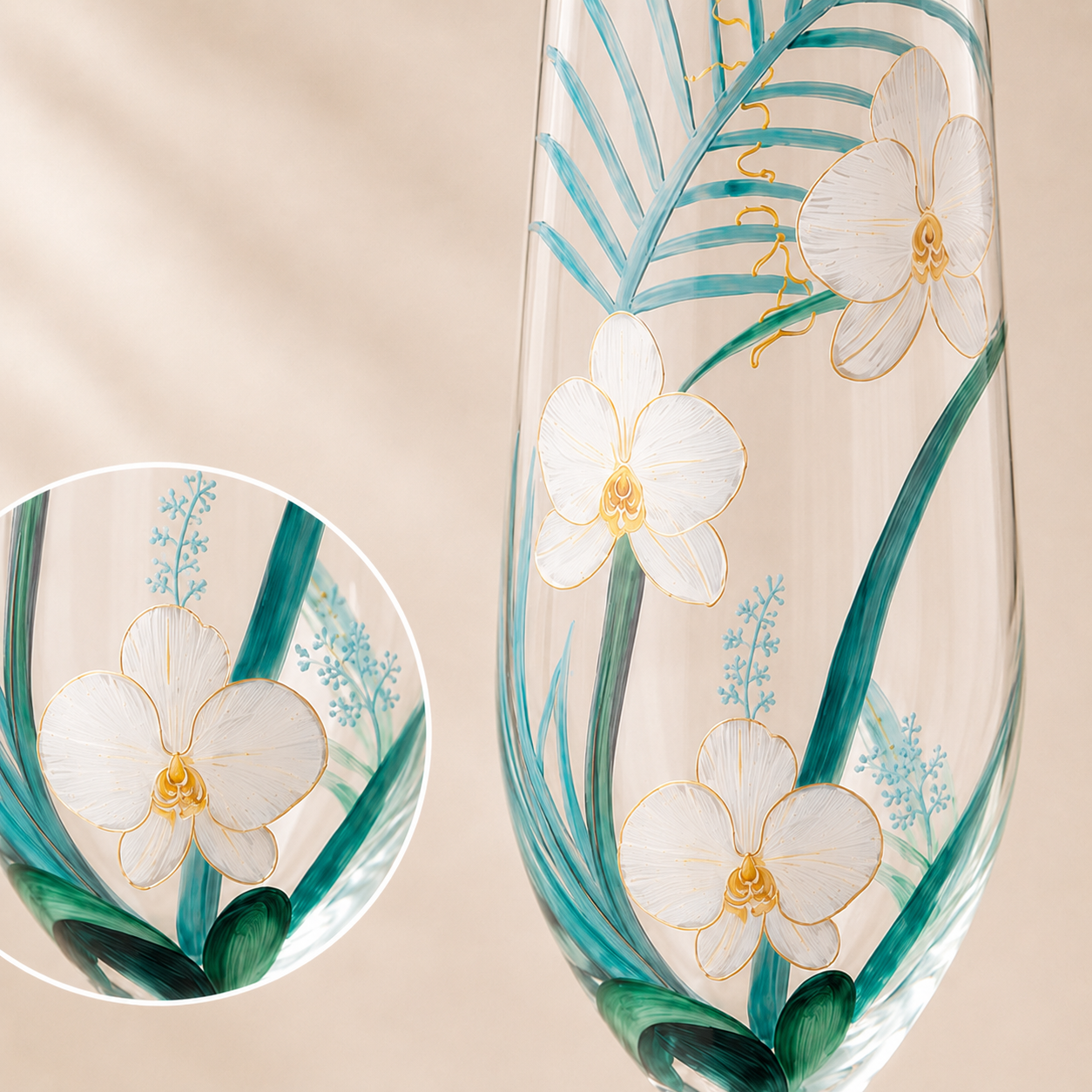 A clear glass flute decorated with hand-painted white orchids, teal tropical leaves, and gold accents, shown against a soft beige background with a circular detail inset.