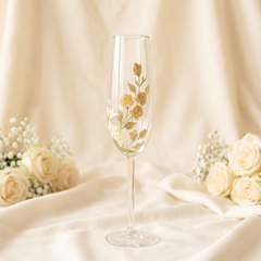 Hand-painted yellow rose champagne flute with ivory botanical flowers on elegant neutral wedding background