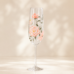 Hand-painted peach and coral floral champagne flute with green leaves on a soft neutral background