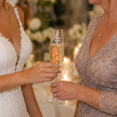 Personalized Groom’s Mother orange floral champagne flute held by bride and mother of groom